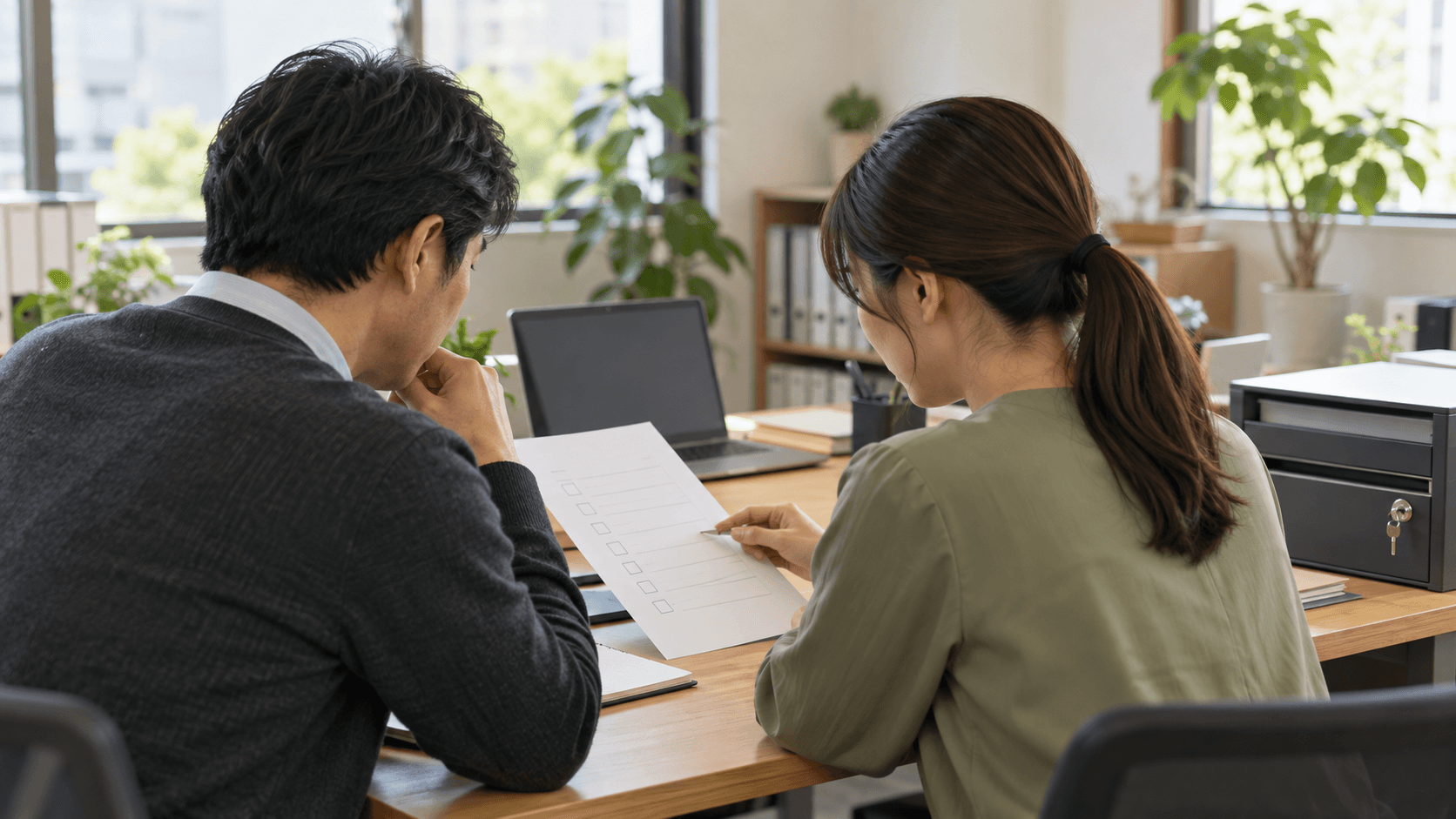 明るいオフィスで、二人の担当者がチェックリストを見ながら利用権限の整理を相談している様子