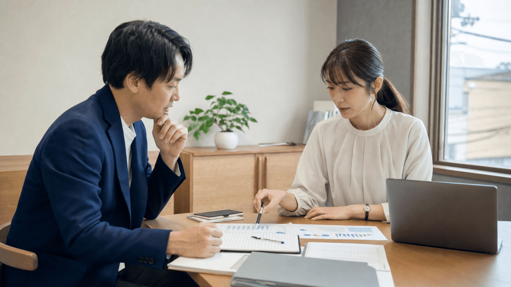 地方企業の会議室で、担当者2人がノートPCと印刷資料を見ながら、AI試験導入の評価項目を確認している様子