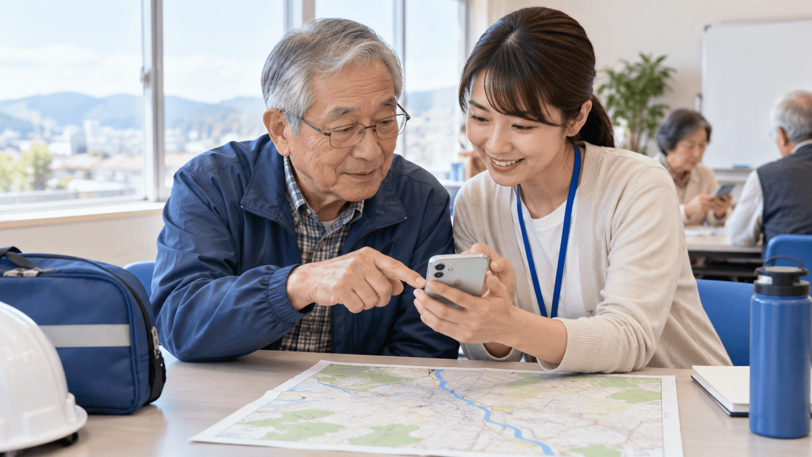 明るい地域教室で講師と高齢の参加者がスマートフォンと紙の地域地図を見比べ、防災情報の確認方法を学ぶ様子