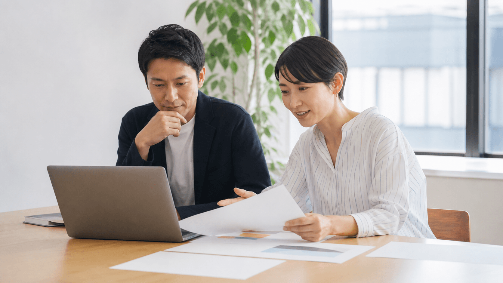地域企業の担当者2人が、ノートPCと無地の資料を見ながら採用ページに載せる情報を話し合っている様子